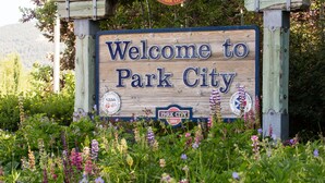 A wooden welcome sign for Park City surrounded by lush greenery and flowers. - Relax, Recharge and Explore at Vantage 71 (Park City)