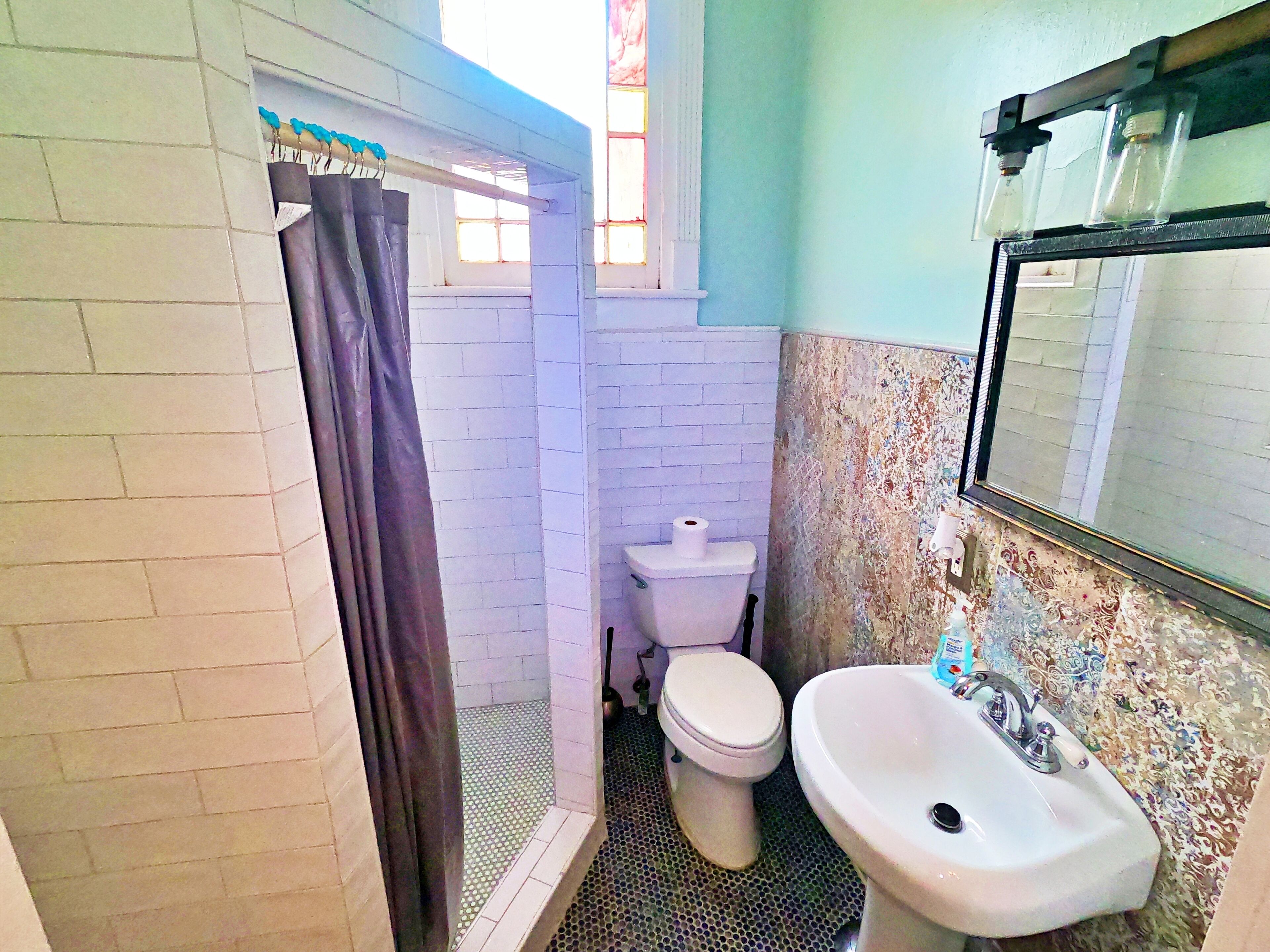 A bathroom with a toilet, sink, and shower area.