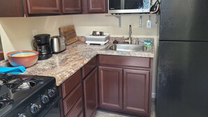 Una cocina con estufa a gas, microondas, lavaplatos y refrigerador.