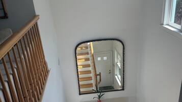 Uma escada com guarda-corpos de madeira, um espelho na parede e um lustre.