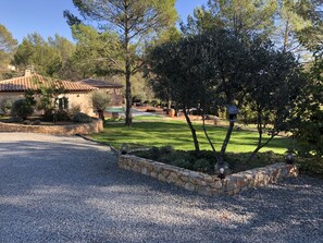 A residential property with a stone retaining wall, a gravel driveway, a lawn, and a house with a tiled roof. - Villa with heated pool (Draguignan)