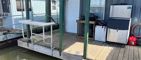 A wooden deck with a table and chairs, a refrigerator, and a water pump.