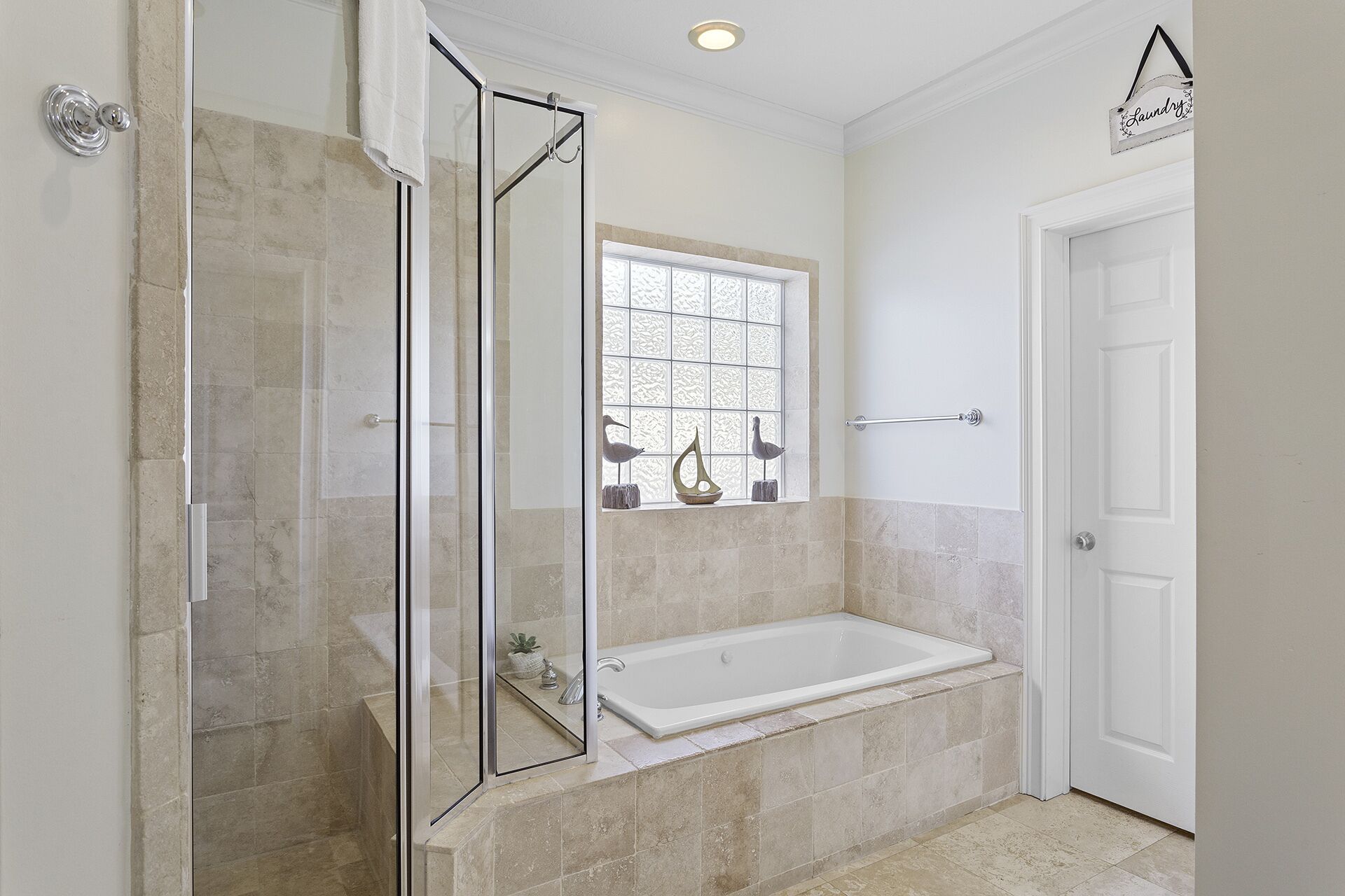 Un baño con cabina de ducha de vidrio, bañera y ventana con adornos.