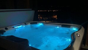 Ein Whirlpool mit blauer LED-Beleuchtung, vor einer nächtlichen Stadtansicht.