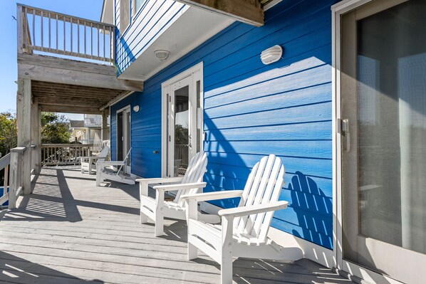 A blue house with a porch, white chairs, and a screened door. - Blue You Away: Oceanside, Private Pool & Hot Tub Rec Room & Pet-friendly (Corolla)