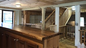 Ein Holzinnenraum mit Barbereich, Treppe und Blick durch eine Tür.