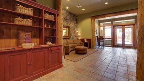 A spacious lobby with a stone wall, wooden shelves, a cushioned seating area, and a tiled floor. - River Run Village Walk To Gondola Pool and Hot Tubs Restaurants and Shops (Keystone)
