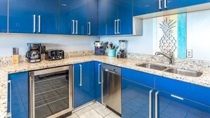 Una cucina moderna con mobili azzurri, forno a incasso, lavastoviglie e piano di lavoro in granito.