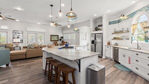A spacious kitchen with a central island, bar stools, and a refrigerator. - Easy Walk to Private Beach! Views, Balconies, Pool, Chef Ready (Destin)