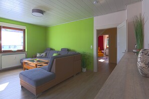 Ein modernes Wohnzimmer mit einem Ecksofa, einem Couchtisch und einer Topfpflanze.