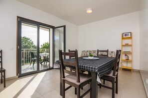 Enjoy meals in this dining area with a table for four, a potted plant, and a sliding door leading to an outdoor space with a view.
