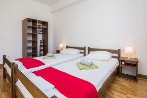 Two single beds with wooden headboards and white bedding, a wooden wardrobe, and bedside tables with lamps.