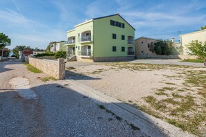 Stunning residential building with balconies, stone wall, and a gravel driveway.