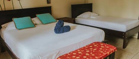 A hotel room with two single beds, a bench, and a wall with red flowers.