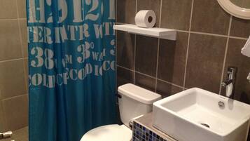 Une salle de bain équipée de toilettes, d’un lavabo et d’un rideau de douche orné de motifs ou d’inscriptions.