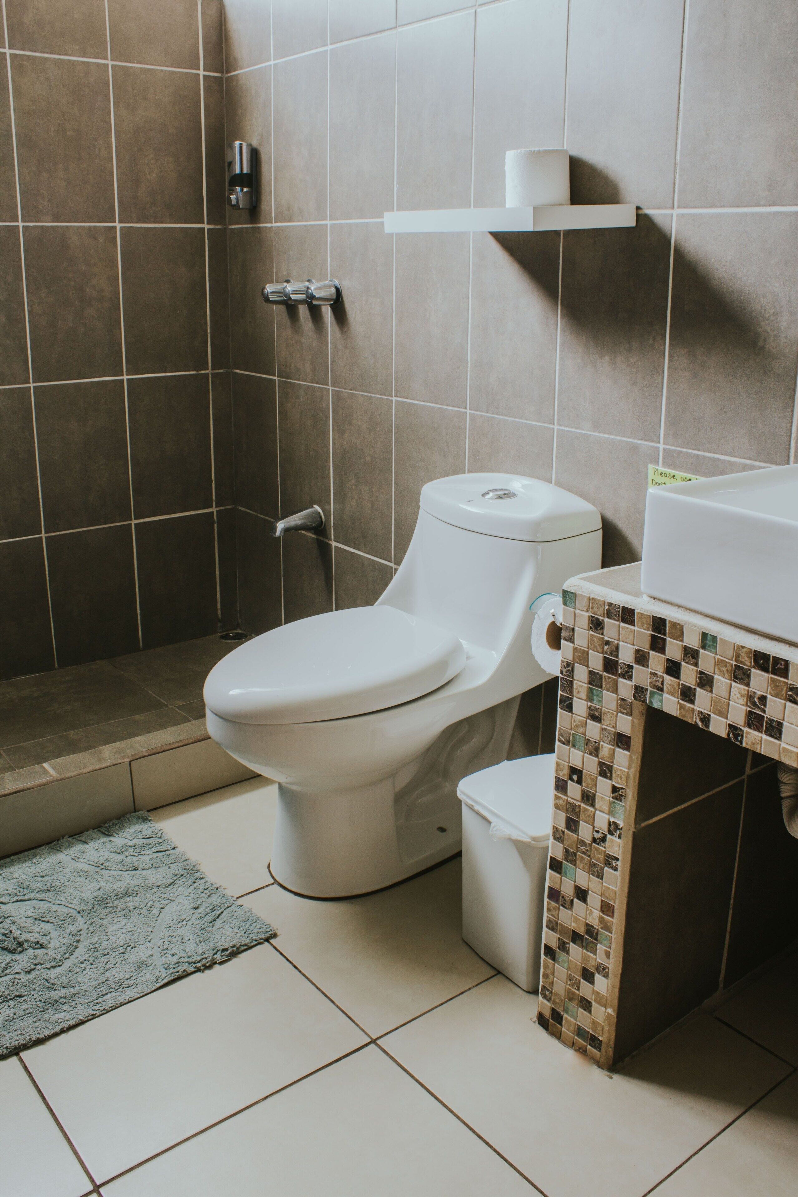 A bathroom with a toilet, a shower area, and a tiled floor.