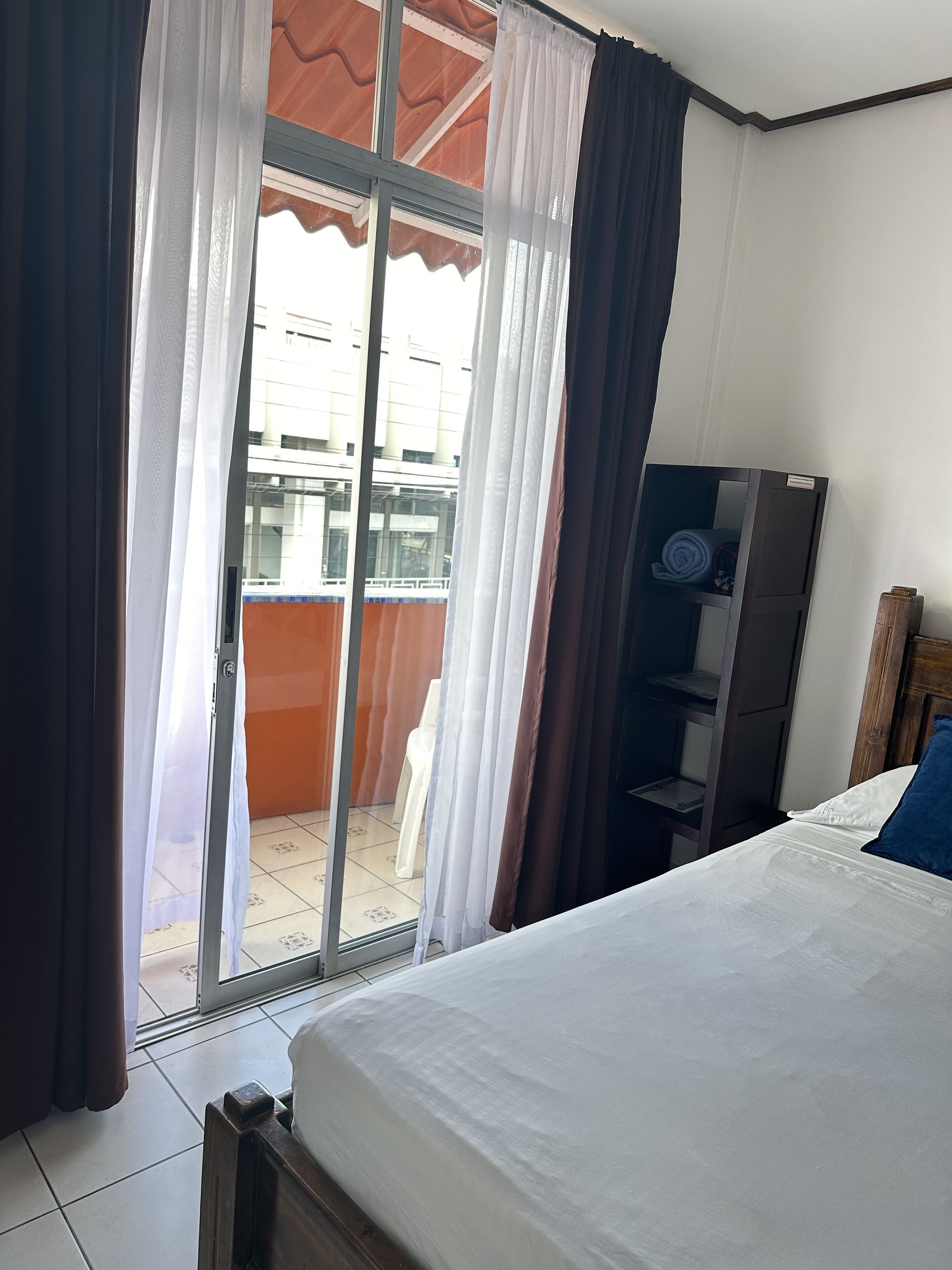 A bedroom with a bed, a wardrobe, and a sliding glass door leading to an outdoor area.