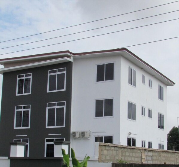 A two-story building with a dark grey and white facade, multiple windows, and a visible air conditioning unit.