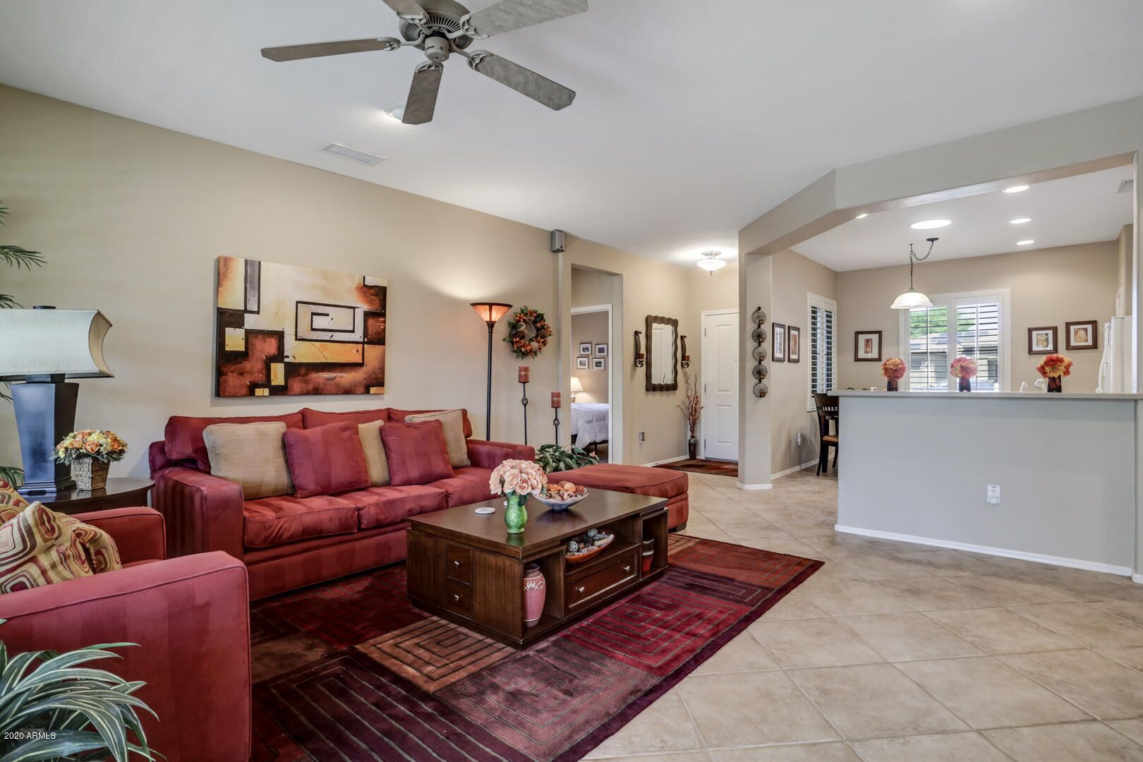 A spacious living room with a red sofa, a coffee table, and a ceiling fan.