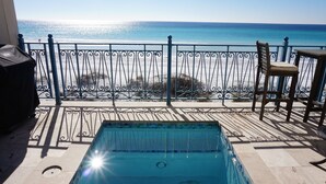 Una piscina con vista sull'oceano, una sedia e un tavolo su un balcone.