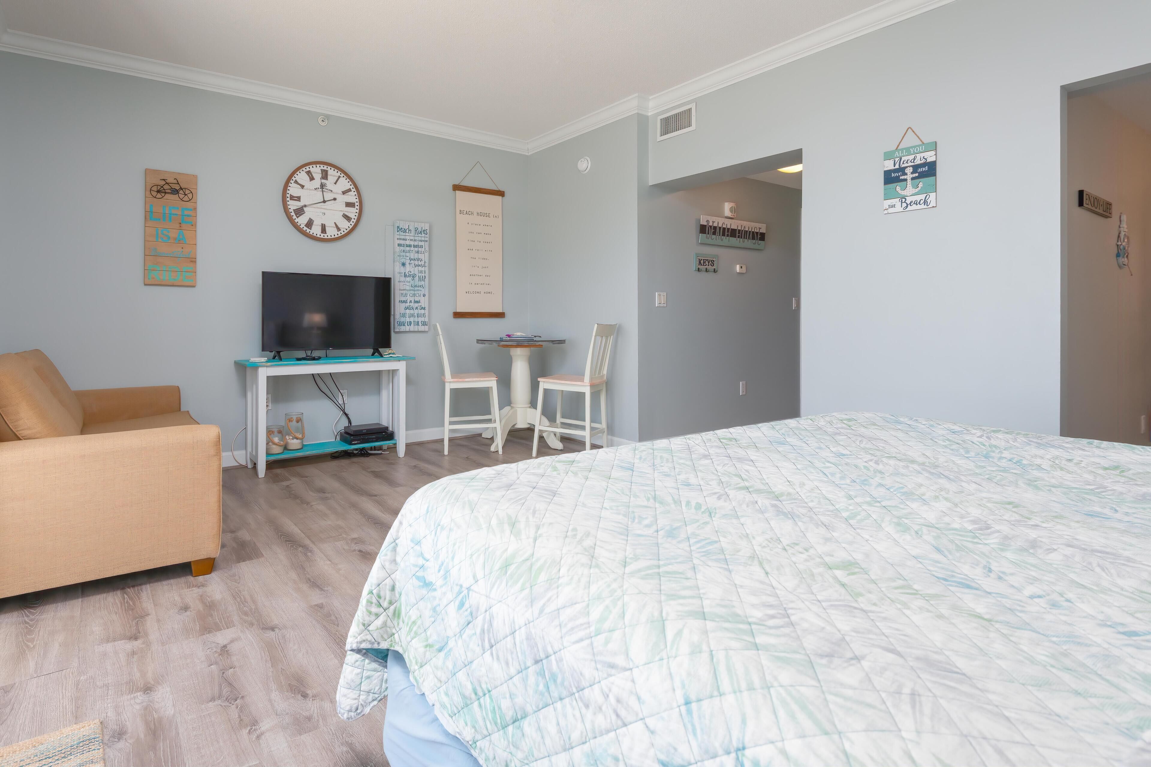 A bedroom with a bed, a TV, a desk, and a chair.