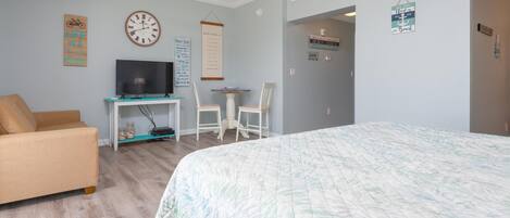 A bedroom with a bed, a TV, a desk, and a chair.