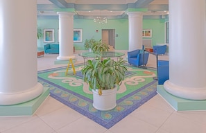 Stunning lobby area with a round table, patterned floor, and elegant columns, surrounded by comfortable seating and beautiful artwork.