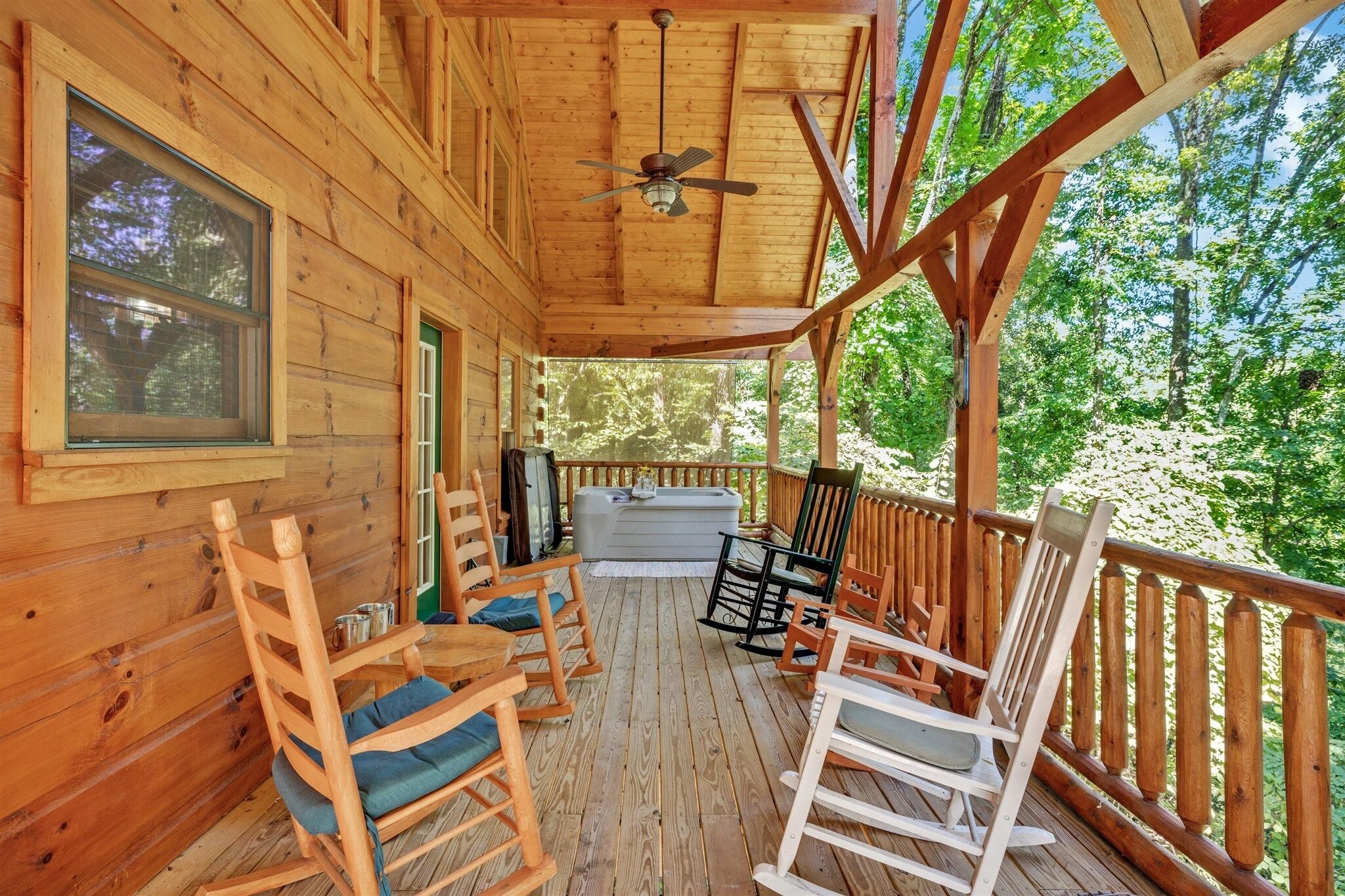 A wooden deck with rocking chairs and a hot tub.