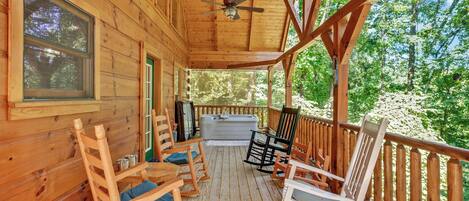 A wooden deck with rocking chairs and a hot tub.