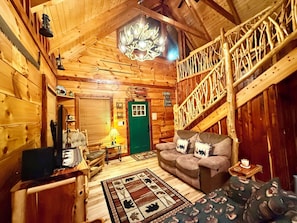 A wooden interior with a green door, a staircase, a sofa, and a chandelier.