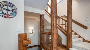 A wooden staircase with a handrail and a wall-mounted clock.