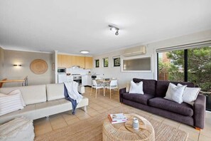 A modern living room with a sofa, a coffee table, and a dining area with chairs.
