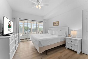 A bedroom with a bed, a nightstand, a dresser, a ceiling fan, and a large window. - Remodeled Condo • Close to Shows, Shopping & Dining (Branson)