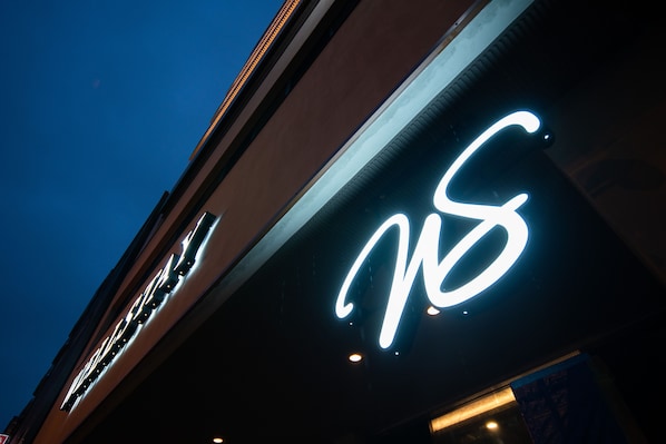 A building with a prominent illuminated sign featuring a stylized 'M' and 'S'. - WellStay Namba 9F (Osaka)