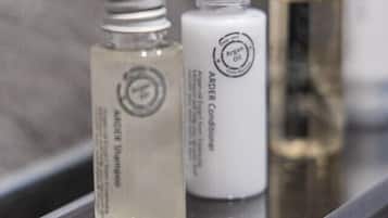 Three bottles of hair care products on a reflective surface.
