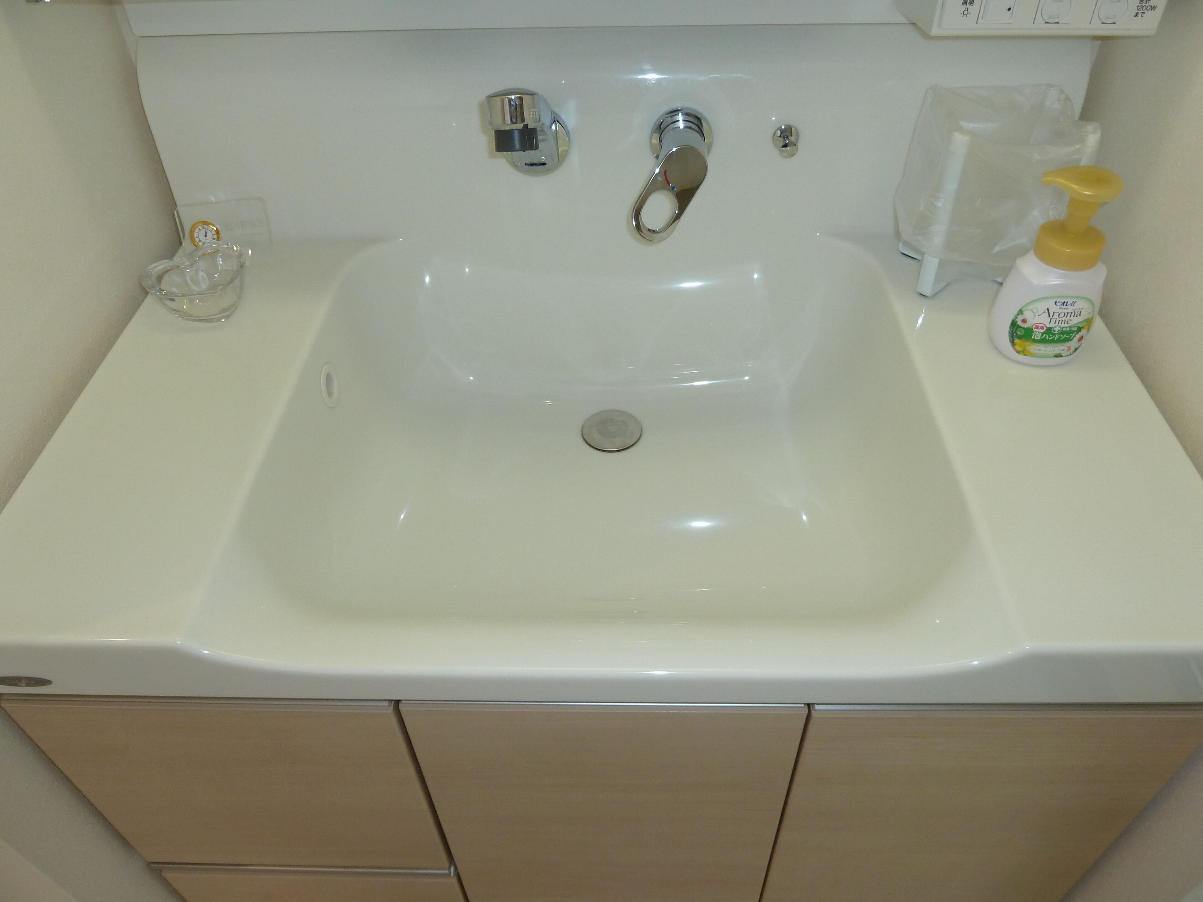 Ein weißes Waschbecken mit einem Chrom-Wasserhahn, einer Seifenspender und einer transparenten Glas-Seifenschale.
