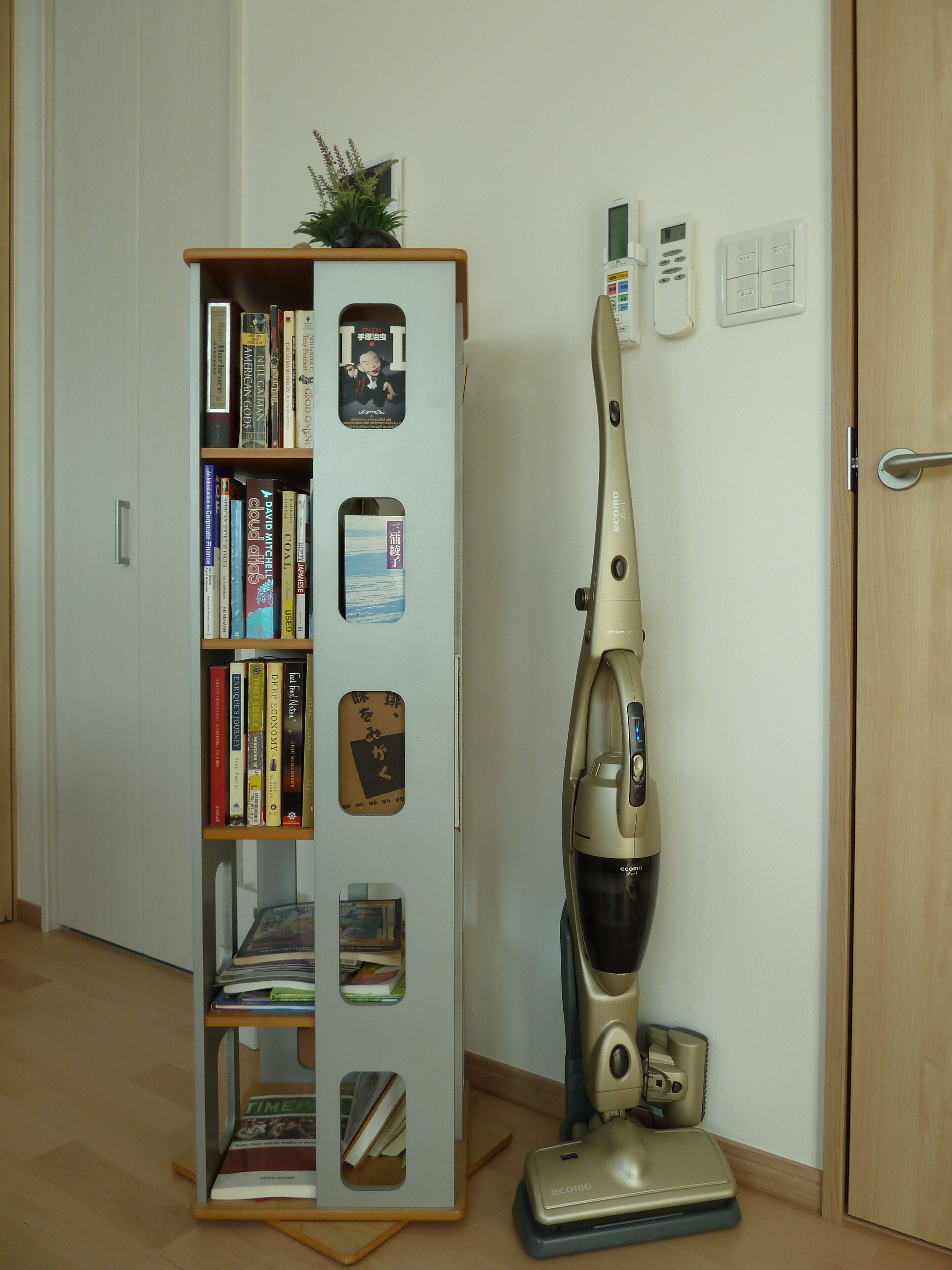 Una habitación con una estantería, un aspirador y una puerta.