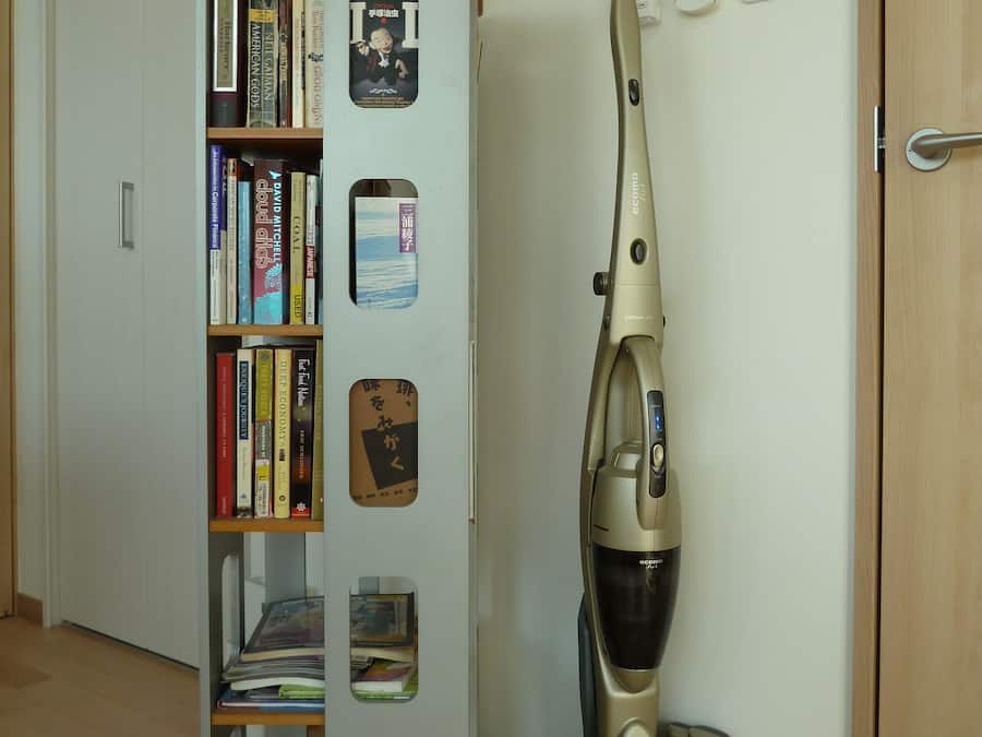 Una habitación con una estantería, un aspirador y una puerta.