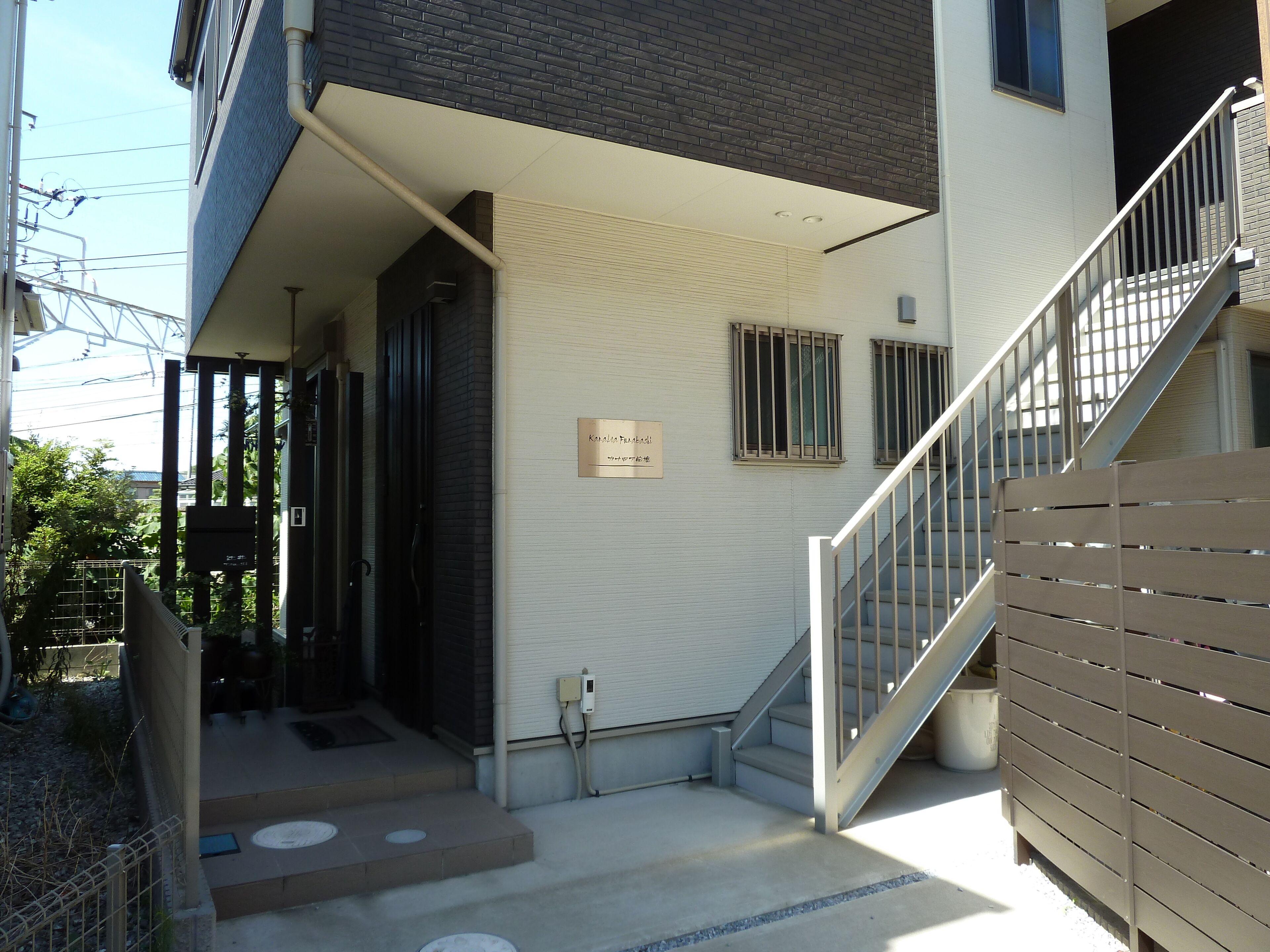 A building entrance with a staircase, a nameplate, and a covered area.