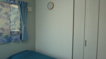A bedroom with a bed, a wardrobe, a clock, and a window with curtains.
