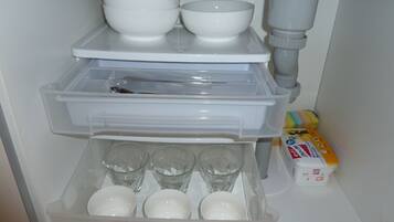A kitchen with a built-in dishwasher, a sink, and a storage area with clear glasses and a box of tissues.