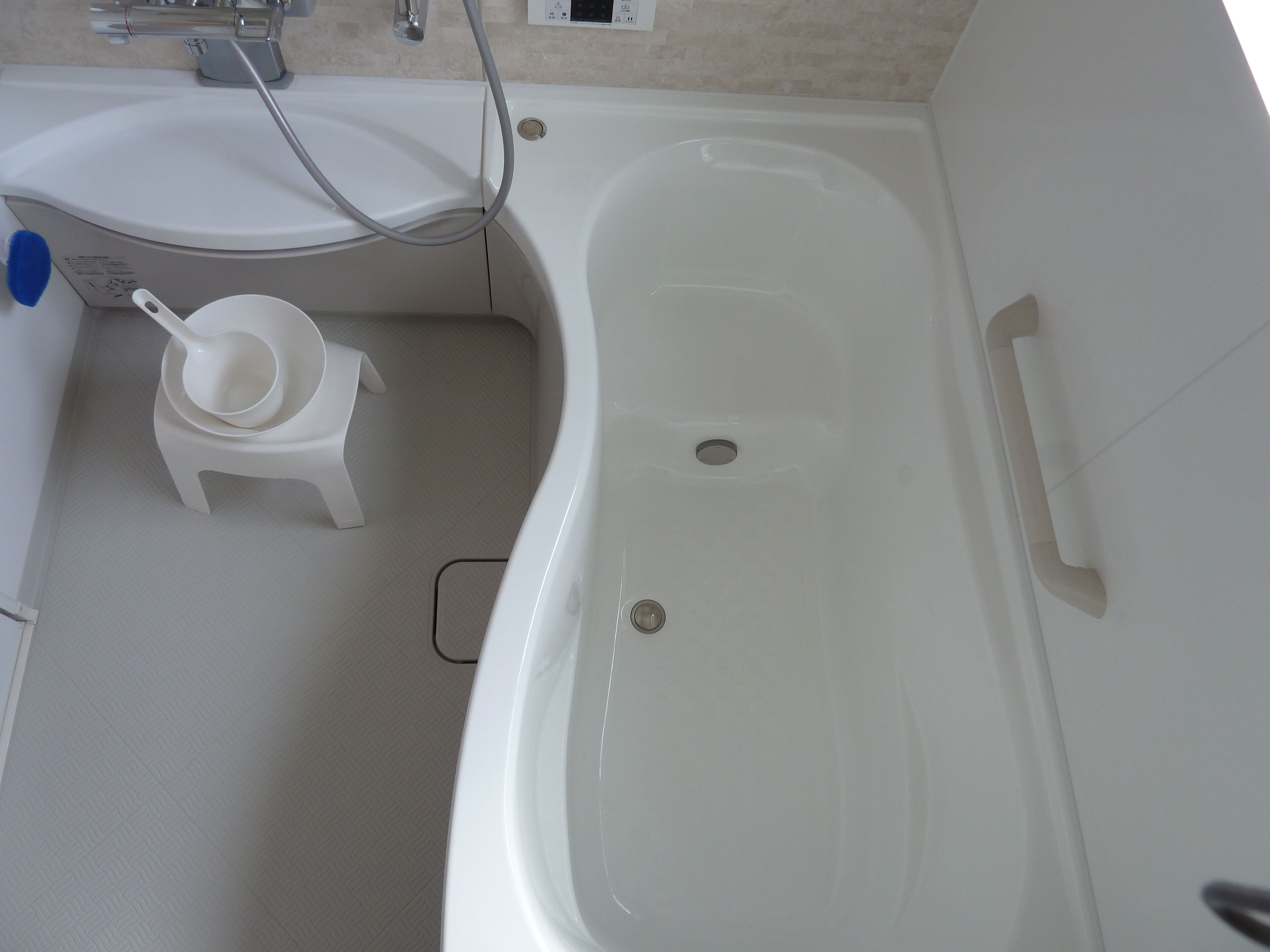 A bathroom with a bathtub, a sink, and a small stool.