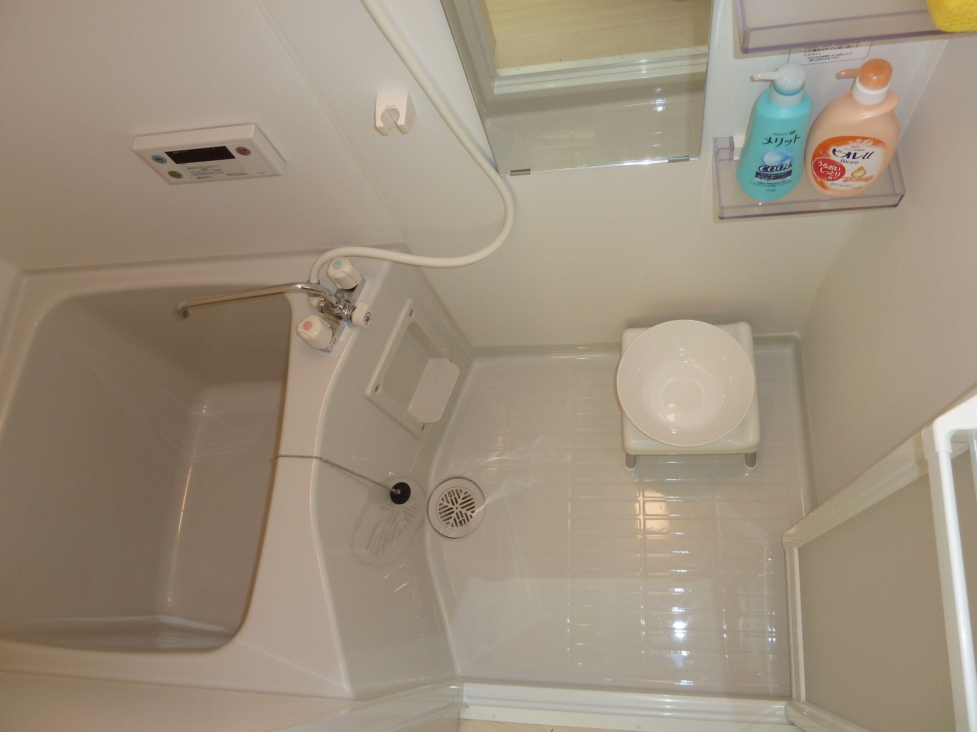 Un baño con bañera, inodoro y estante con artículos de aseo.