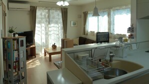A compact living space with a kitchenette, a dining area, a TV, and a bookshelf. - Kanaloa Funabashi (Funabashi)