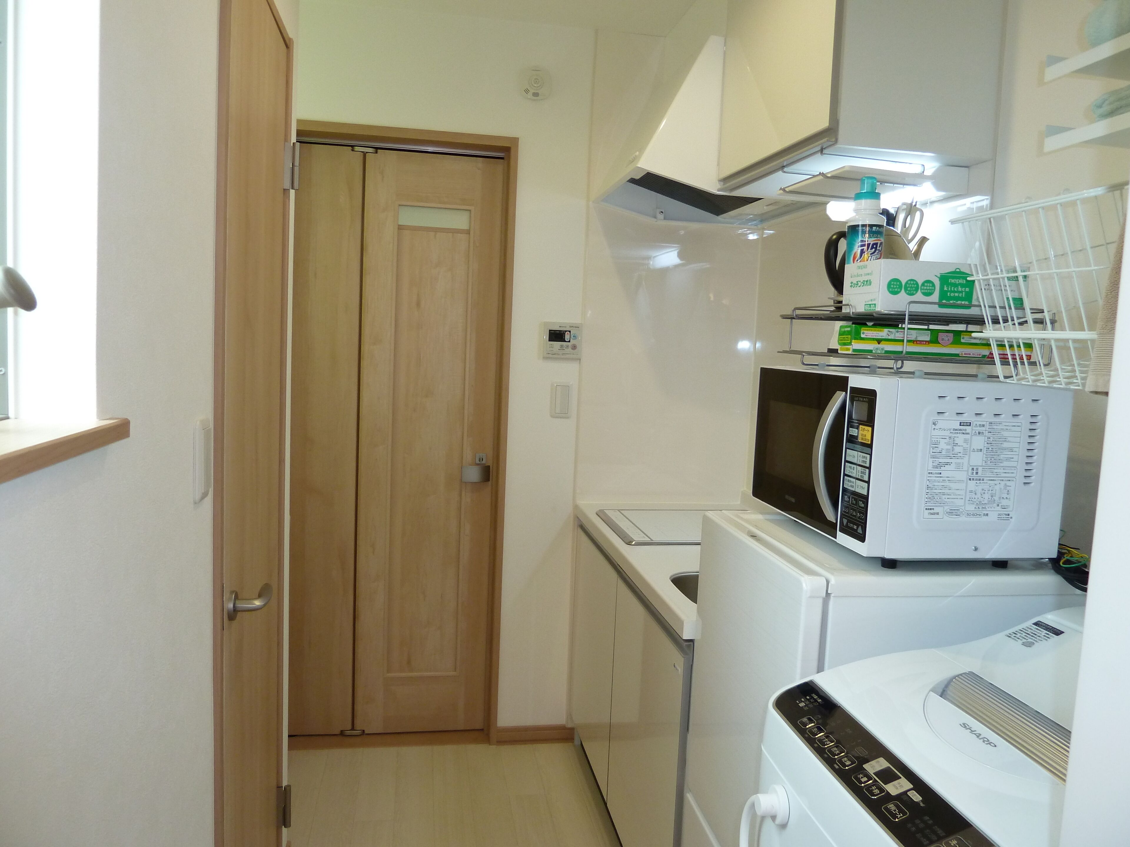 Cocina compacta con microondas, tostadora y refrigerador pequeño.
