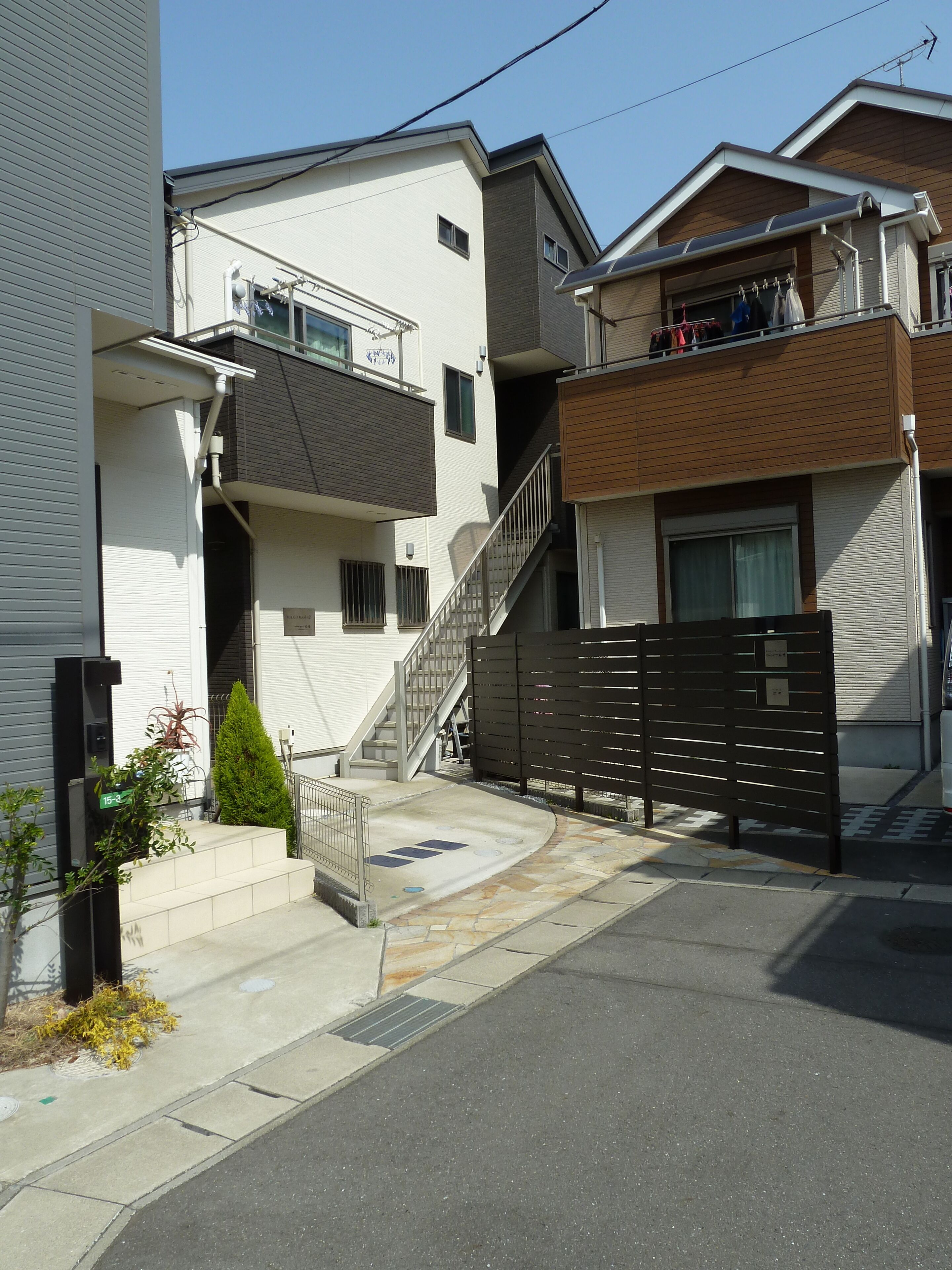 A residential area with modern houses, a gated entrance, and a small staircase leading to a balcony.