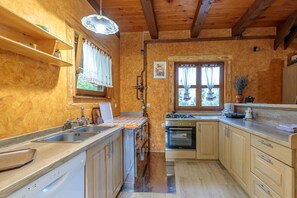 Eine Küche mit Holzausstattung, einem Geschirrspüler, einem Herd und einem Fenster mit Vorhängen.