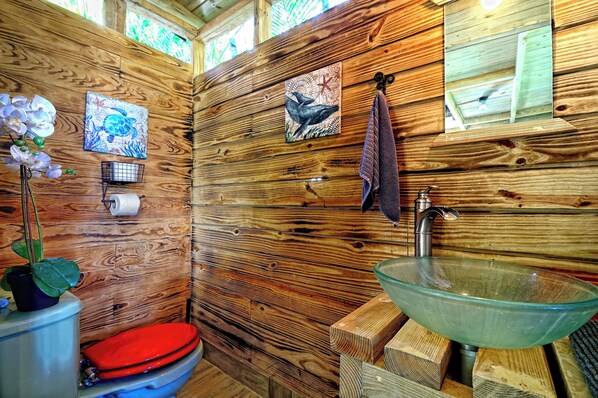 A wooden cabin bathroom with a glass sink, a red toilet, and wooden walls. - Brand new 3 design eco lofts, 5 bedrooms, fits 15 people (Cabarete)
