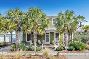 Stroll up to this charming two-story home, featuring a welcoming front door and a cozy porch with comfortable seating.