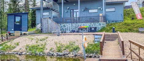 Un edificio moderno con piscina, muelle de madera y un pequeño embarcadero.